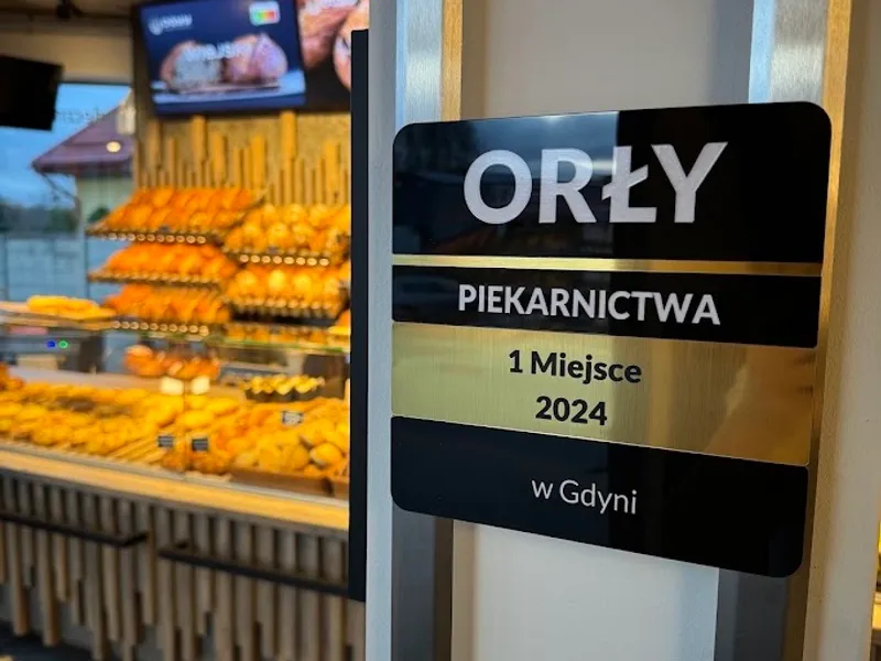 Tabliczka „Orły Piekarnictwa — 1. miejsce 2024 w Gdyni” przy witrynie sklepu OGYY